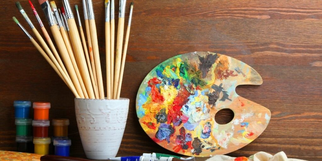 Une palette de peinture et des pinceaux, représentant le 3e art