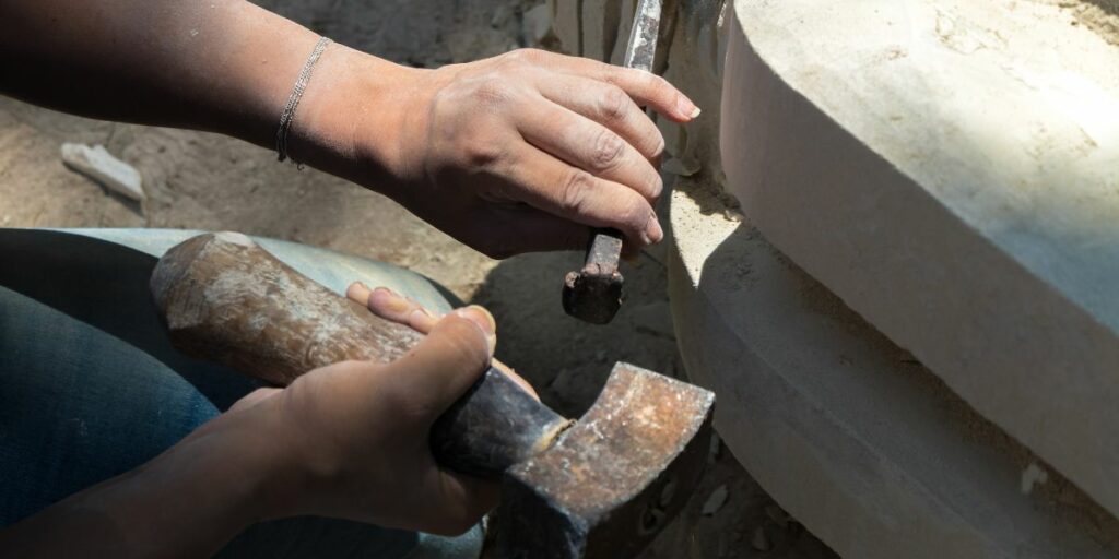 Un artisan en train de planter un clou avec un marteau